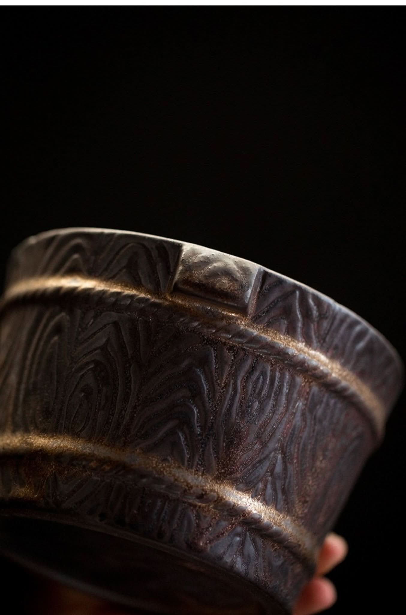 Dark brown pottery Japanese tea jar with textured wood grain design and gold accents.